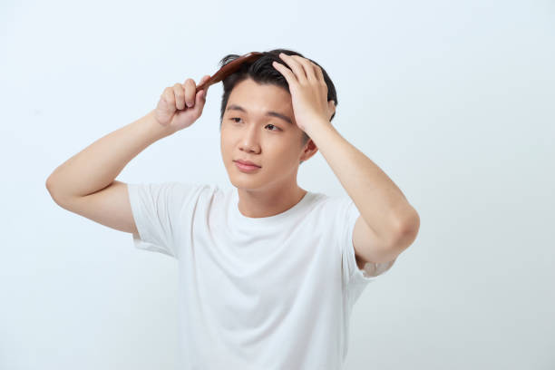 istock Smiling young man brushing hair with comb on white background 1251661893