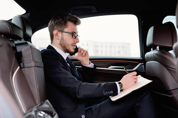 istock Businessman writing in notebook in luxury car 1251662753