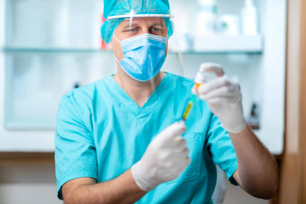 istock Doctor in protective mask and visor pulling vaccine out from vial 1251662921