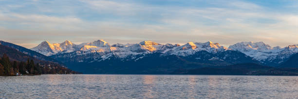 atemberaubender panoramablick auf berühmte schweizer alpengipfel auf dem berner oberland eiger nordwand, monch, jungfrau in der dämmerung vom thunersee an einem sonnigen herbsttag mit blauer himmelswolke,bern, schweiz - bernese oberland thun oberland panoramic stock-fotos und bilder