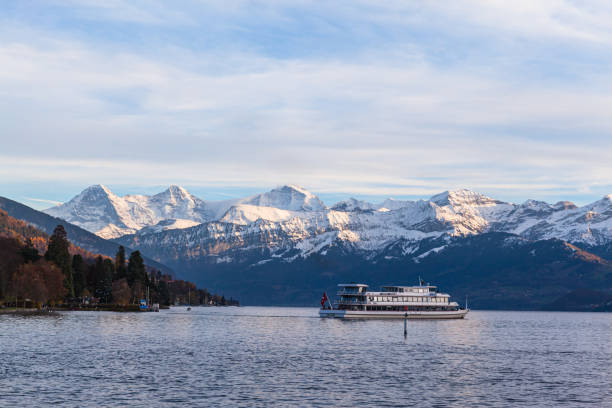 atemberaubender panoramablick auf berühmte schweizer alpengipfel auf dem berner oberland eiger nordwand, monch, jungfrau in der dämmerung vom thunersee am sonnigen herbsttag mit kreuzfahrtschiff, bern, schweiz - bernese oberland thun oberland panoramic stock-fotos und bilder