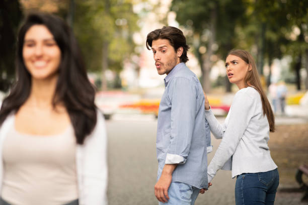 Jealous Girlfriend Calling Boyfriend Distracted By Other Attractive Woman Jealousy. Jealous Girlfriend Calling Boyfriend Distracted By Other Attractive Woman Walking During Date In Park. Selective Focus boyfriend stock pictures, royalty-free photos & images