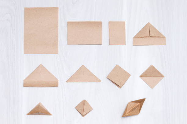 Steps of making origami paper boat on white wooden background. Steps of making origami paper boat on white wooden background. origami instructions stock pictures, royalty-free photos & images