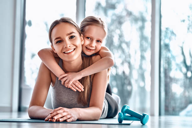 ジムで親子。小さな女の子は休んでいる間、母親の背中に横たわっています。 - offspring child lying on back parent ストックフォトと画像