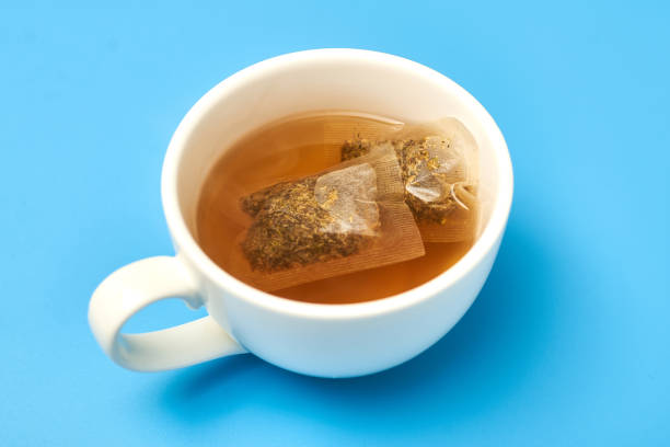istock Tea bag in a white cup on a blue background. Making delicious herbal tea. 1251665124