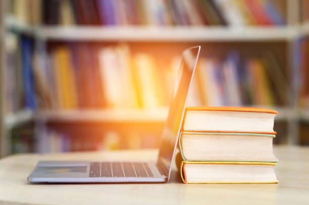 Close up of open laptop and pile of books Digital Education And E-learning. Open laptop and stack of old books in blur school library or classroom background handbook photos stock pictures, royalty-free photos & images