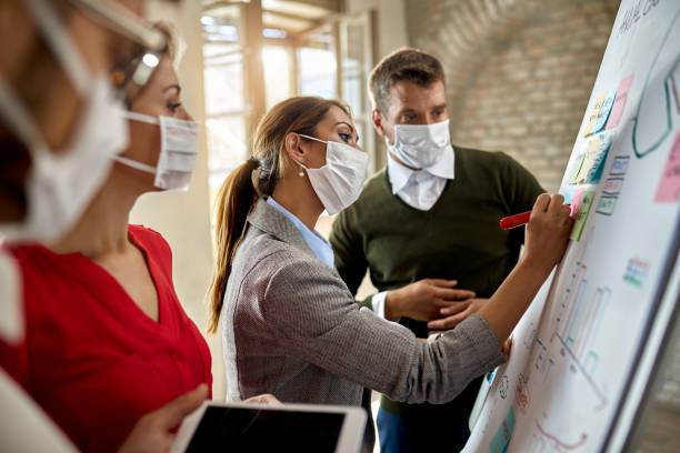 team of business people with face mask brainstorming on whiteboard in the office. - writing whiteboard men businessman imagens e fotografias de stock