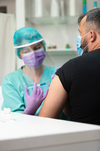istock Injecting male patient with Coronavirus vaccine 1251667508