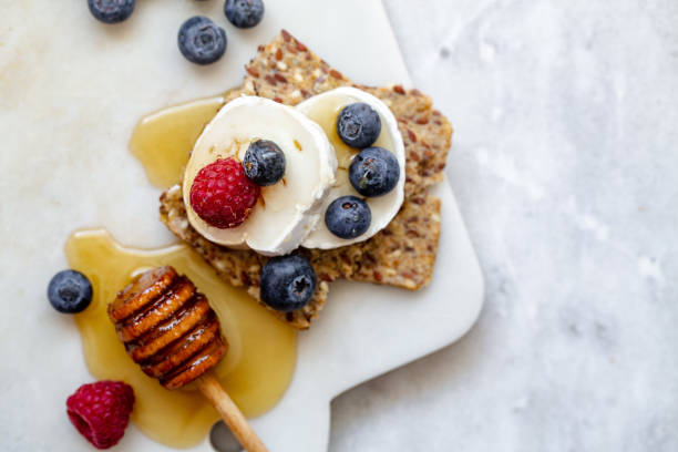 spuntino con pane croccante, formaggio di capra e frutta fresca su sfondo marmo bianco. concetto di cibo sano - strawberry sandwich crispbread goat cheese foto e immagini stock