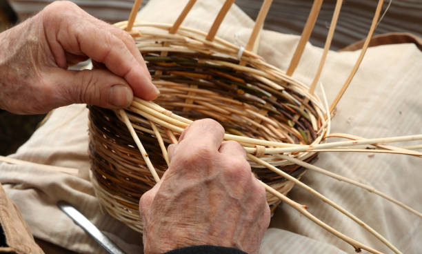 istock elderly craftsman while weaving a wicker basket at the market 1251669021