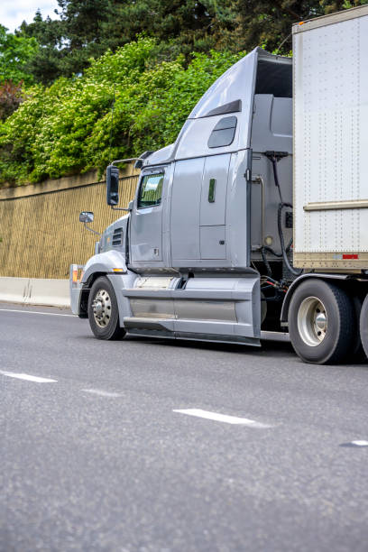 istock Gray big rig long haul semi truck with high cab and sleeping compartment transporting loaded dry van semi trailer running on the highway with concrete wall on the hillside 1251670046