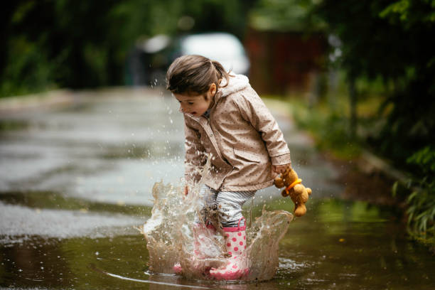 행복한 어린 소녀 점프 에 이 비 스톡 사진 - puddle rain child splashing 뉴스 사진 이미지