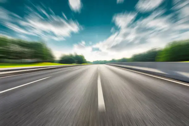Photo of Fast moving road and green forest landscape.