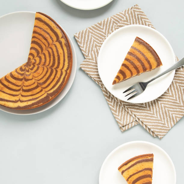 Marble cake (zebra) on light grey background. Pieces on white plates.
