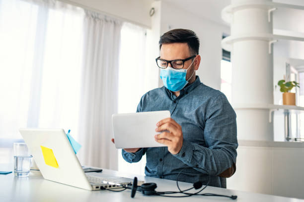 istock Man surfing the internet wearing a facemask. 1251688048