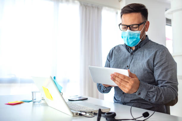 istock Man surfing the internet wearing a facemask. 1251688109