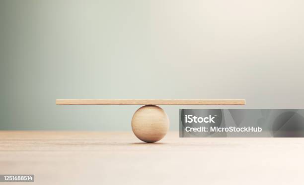 Wooden Seesaw Scale Sitting On Wood Surface In Front Of Defocused Background Stock Photo - Download Image Now
