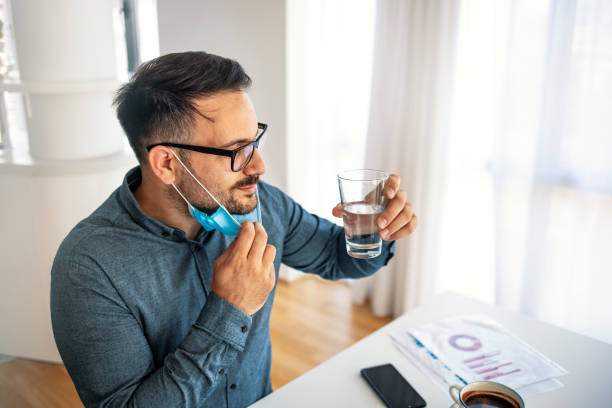 geschäftsmann mit maske trinkwasser bei der arbeit. - business relationship white collar worker office glasses stock-fotos und bilder