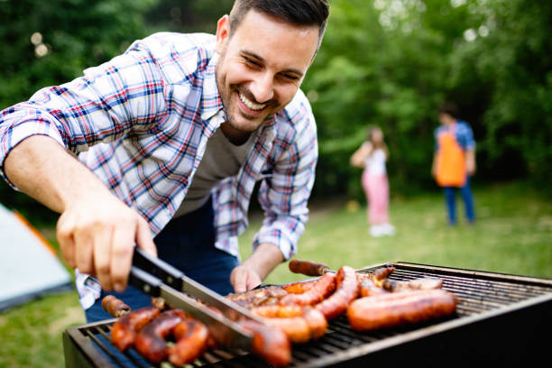 guapo macho preparando barbacoa, parrilla al aire libre para los amigos - sausage barbecue grill barbecue cooking fotografías e imágenes de stock