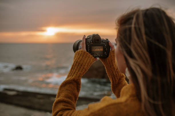 istock Young woman using a DSLR camera at sunset 1251690320