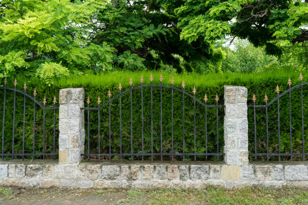 istock Fence with stone columns,  green grass and trees 1251692879