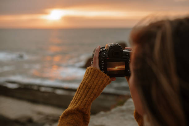 istock Young woman using a DSLR camera at sunset 1251692954