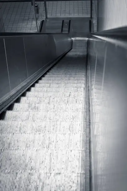 Looking down an empty escalator in a commercial building to the floor below with focus to the moving treads