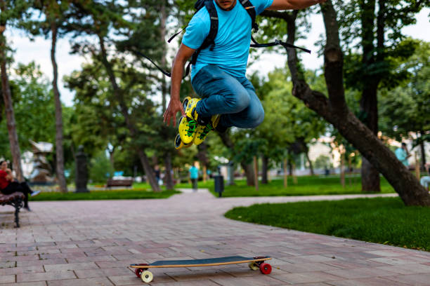 istock Man jumps with inline skates over a longboard 1251699108