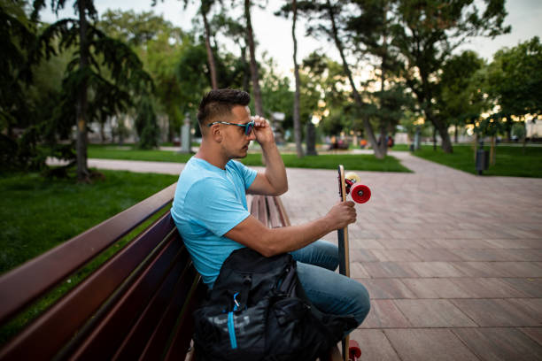 istock Young man with longboard enjoys in city park 1251699315