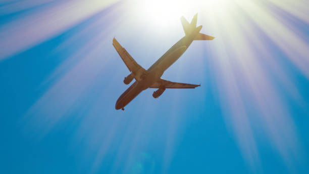 istock Airplane gaining height after taking off. Jet flying against blue sky and sun 1251700049