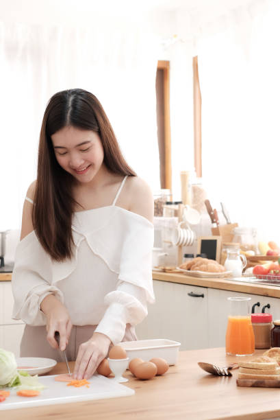 istock Cute woman slicing ham for made sandwich in kitchen. 1251708581