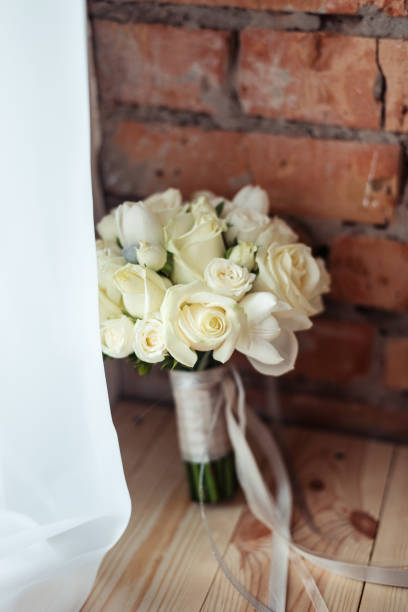 Wedding bouquet of white roses in a rustic style on a brick wall background