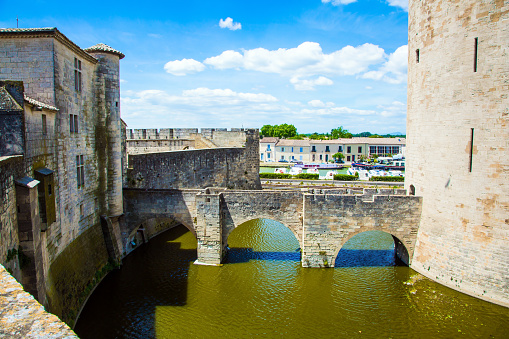 Powerful walls and a moat with water surround the ancient city of Aigues-Mortes. Mediterranean coast of France. The concept of active, historical and photo tourism