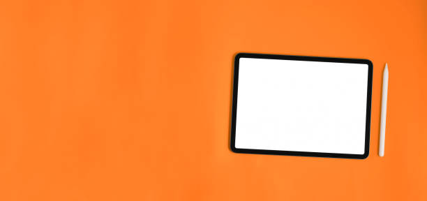 istock Computer tablet and stylus pen are putting together on orange background. 1251716569