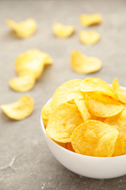 istock Potato chips on bowl on grey concrete background. Top view 1251719297