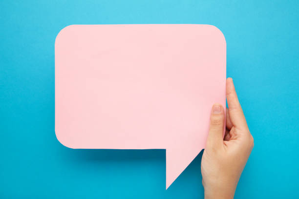 istock Hand holding an pink empty speech bubble on blue background 1251719653
