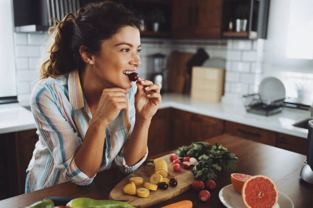 朝の健康的な朝食を持っている若い笑顔の女性 - women eating fruit food ストックフォトと画像