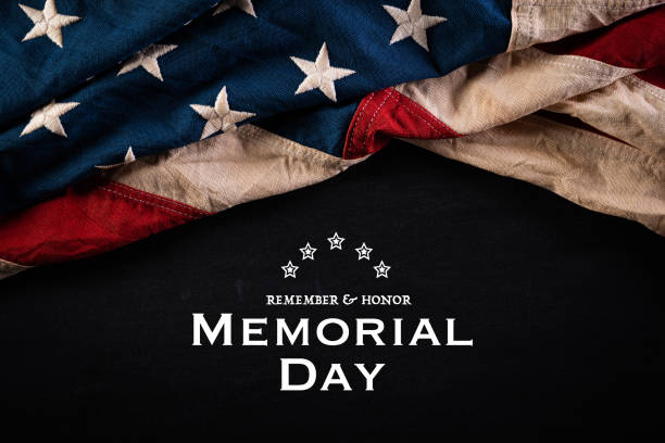 istock Happy Memorial Day. American flags with the text REMEMBER & HONOR against a blackboard background. May 25. 1251721505