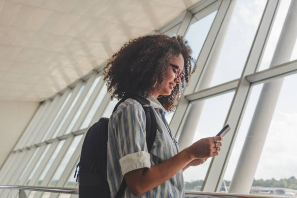 istock Young woman with backpack checking her boarding schedule at the airport 1251725183