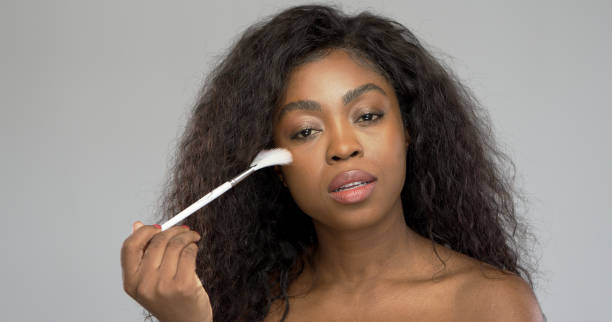 African American woman applying makeup stock photo