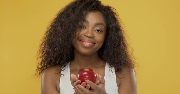 istock Positive ethnic female sharing apple with camera 1251725867