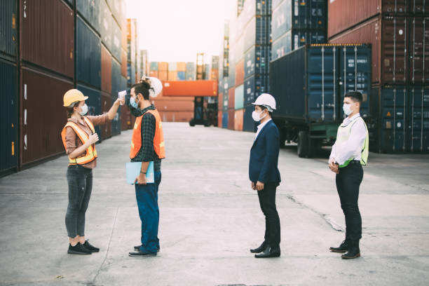 istock Temperature measurement with employee temperature meter before entering work at container yard 1251729474