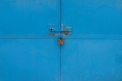 Old blue lock hanging on blue garage door. grundge aged  rusty Padlock .