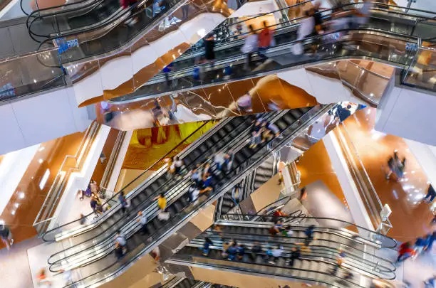 People on many fast moving Escalators In big modern shopping mall. Consumption concept Customers clients moving on escalator staircases