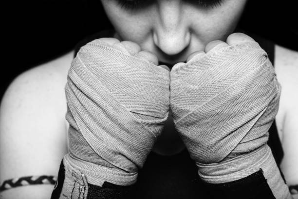 muay thai chica luchadora preparándose para la batalla. retrato en blanco y negro sobre fondo negro. - ready to fight fotografías e imágenes de stock