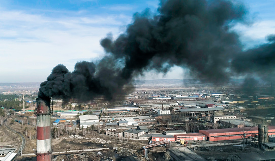 Aerial footage of coal-fired plant smokestack. Black smoke cloud is coming from chimney. 4K