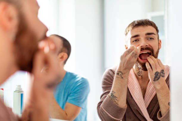 istock Bathroom mirror image of man cleaning teeth with dental floss 1251739933
