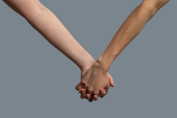 istock Close-up of light-skinned and dark-skinned people holding hands 1251743758