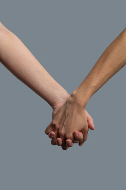 istock Close-up of light-skinned and dark-skinned people holding hands 1251743762