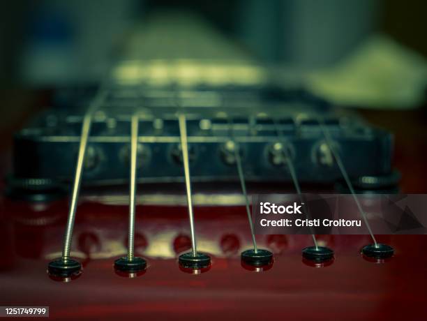 Close Up With A Guitar Bridge And Strings Red Guitar With Blurred Background Stock Photo - Download Image Now